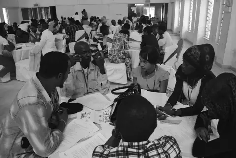 People discussing around a table in an earlier citizen dialogue in the Gambia.