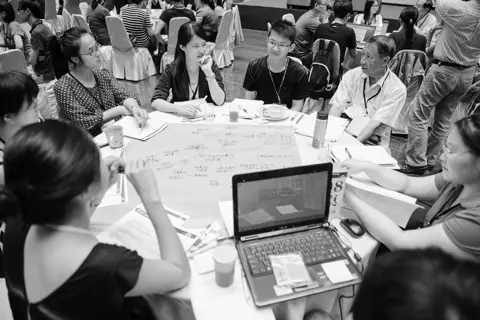 People discussing around a table in an earlier citizen dialogue in Taiwan.